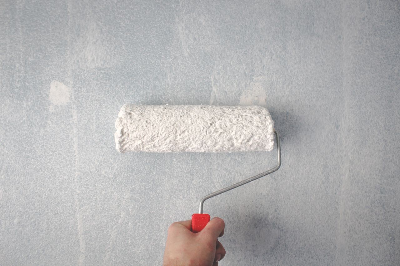 %titre de l'article% Personne repeignant un mur au rouleau pour relooker une pièce